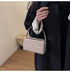 Detail of light beige box handbag with quilted leather and golden fashion lettering