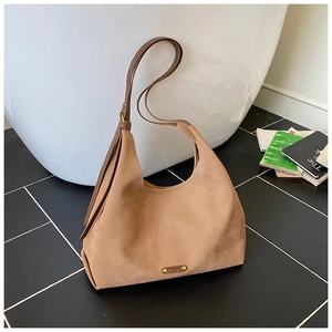 Close-up of brown suede bucket bag featuring a golden metal 'NICE DAY' logo plaque