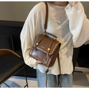 Detail of vintage dark brown crossbody bag with gold lettering and metallic buckle