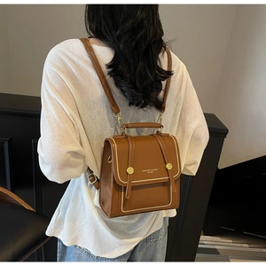 Rear view of a model wearing the brown leather backpack with golden rivet details