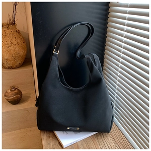 Detail of black matte hobo bag with metal logo on a wooden surface in a minimalist room