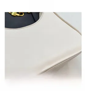 Detail of off-white leather shoulder bag featuring silver text and premium gold hardware