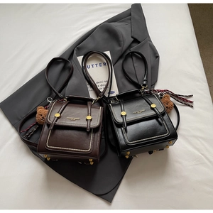 Detail of retro leather bags featuring golden rivets and a plush bear charm accessory