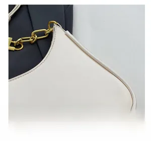 Detail showing the cream leather texture and gold chunky chain strap of the shoulder bag