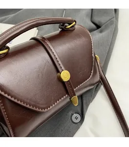 Detail of dark brown leather Boston bag showing smooth PU texture and bronze metal lock