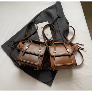 Detail of vintage faux leather backpacks in brown and caramel with plush bear charms