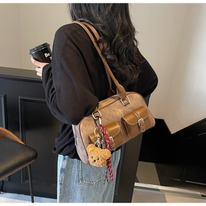 Detail of vintage brown leather Boston bag featuring front pockets and plush bear charm