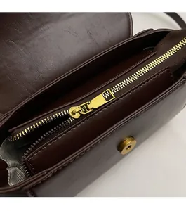 Detail of smooth metal zipper and magnetic buckle on dark brown leather boston bag