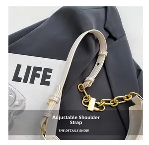 Detail of white leather shoulder strap with gold chain and adjustable buckle design