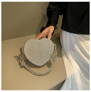 Gros plan d'un sac de soirée en forme de cœur avec strass argentés et chaîne à nœud