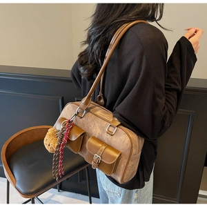 Detail of vintage brown Boston bag with utilitarian front pockets and plush bear charm