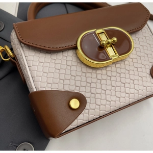 Detail of woven texture and gold metal turn-lock on the brown and beige flap handbag