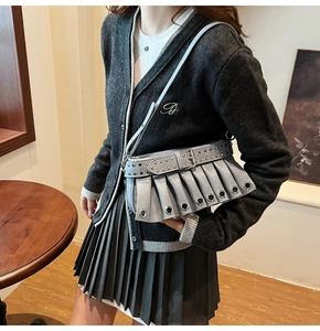 Detail of grey-blue pleated shoulder bag with metal eyelets and rivets on a model