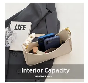 Internal capacity of minimalist beige underarm bag showing space for phones and lipstick
