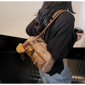 Detail of vintage brown Boston bag featuring dual front pockets and a cute teddy bear charm