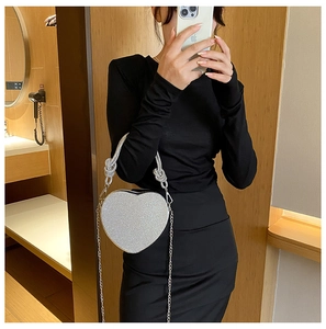 Détail macro d'un sac à main argenté en forme de cœur avec strass brillants et chaîne