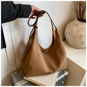 Close-up of brown matte hobo bag with adjustable strap and metal logo on soft texture