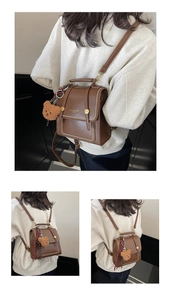 Detail of dark brown vintage small backpack featuring a plush bear charm and gold metal stud