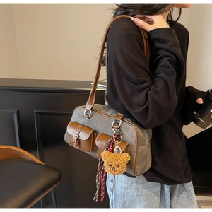 Side view of retro canvas shoulder bag with leather trim and plush bear charm detail