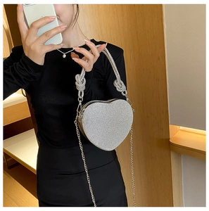 Détail d'un sac de soirée argenté en forme de cœur avec strass brillants et poignée tressée