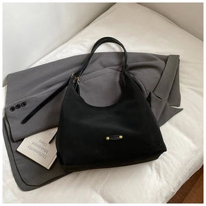 Detail of black matte bucket bag with gold metal logo on a grey blazer outfit