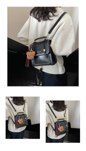 Detail of black leather backpack featuring white stitching, gold hardware and plush bear charm