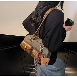 Detail of vintage canvas Boston bag with leather pockets and cute teddy bear charm