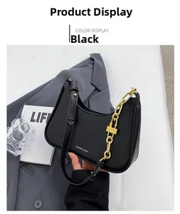Detail of black leather crescent underarm bag featuring a golden metal chain and logo