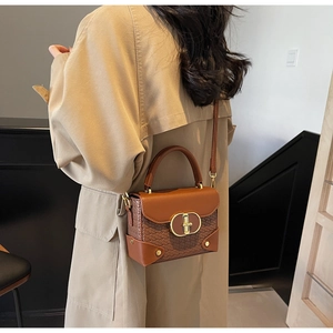 Detail of vintage woven leather crossbody bag with gold buckle on a beige trench coat