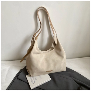 Close-up of cream matte suede bucket bag with metal logo detail and adjustable strap