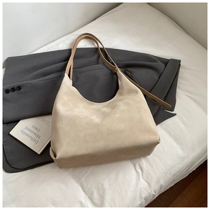 Detail of minimalist beige matte suede bucket bag with slim brown leather straps