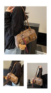 Retro brown Boston bag with front pockets and plush bear charm in a modern interior