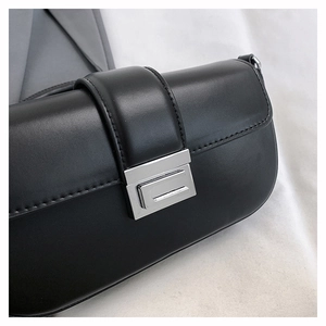 Close-up of black leather bag featuring a polished silver rectangular twist-lock clasp