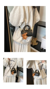 Détail du mini sac boston noir en cuir grainé avec charm ours en peluche sur le mannequin