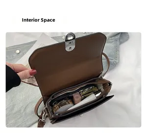 Detailed interior of the brown crossbody bag showing main compartment and zippered pocket