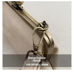 Close-up of detachable bronze hook and crocodile embossed texture on beige handbag