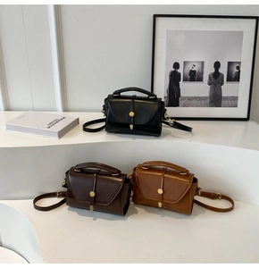 Retro Boston handbags in black, dark brown, and caramel colors on a white display stand