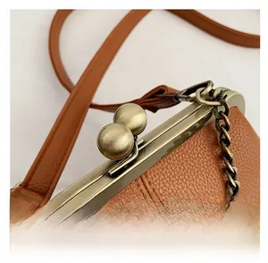 Vue macro du fermoir en bronze et du cuir grainé litchi sur un sac à main marron