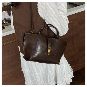 Détail d'un sac cabas vintage en cuir marron foncé avec boucle dorée sur un mannequin