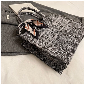 Dettaglio della borsa tote paisley ricamata con manico in seta e striscia logo