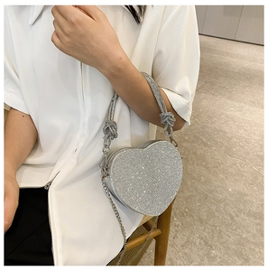 Détail du sac de soirée argenté en forme de cœur orné de strass et d'une anse nouée
