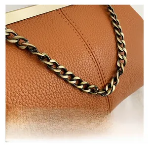 Détail du sac coquille en cuir grainé marron avec chaîne en bronze et cadre doré chic