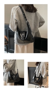 Detail view of glossy black hobo bag with vintage metal buckle and adjustable shoulder strap
