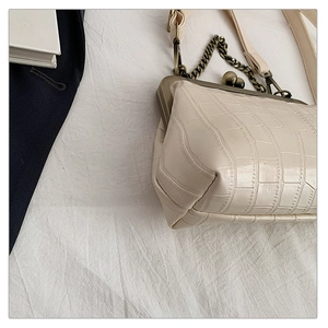 Detail of cream white faux crocodile leather handbag with vintage bronze clasp