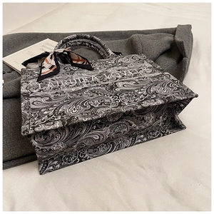 Dettaglio della borsa tote in tela con stampa paisley e foulard decorativo su sfondo beige