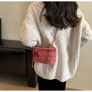Detailed back view of pink tweed chain bag worn with a white cable knit sweater