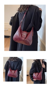 Detail view of retro burgundy glossy leather hobo bag with pin buckle and classic strap