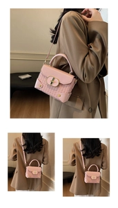 Detail of light pink crossbody bag with woven texture, gold twist lock, and metal studs