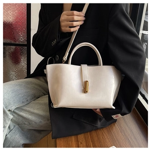 Cream off-white leather tote bag with gold metal buckle shown in a lifestyle setting