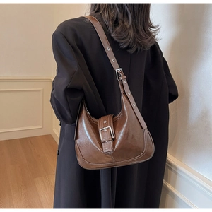 Detail of a brown hobo shoulder bag with glossy PU leather and silver buckle strap